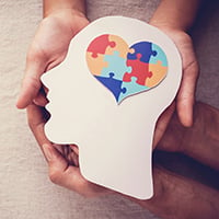 Hands holding a jigsaw puzzle and head silhouette to symbolize Mental Health awareness