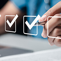 medical professional in front of a laptop with a pen creating checkmarks