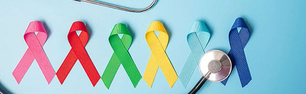 Pink, Red, Green, Yellow, Teal, and Blue Cancer Ribbons on blue background with stethoscope surrounding them